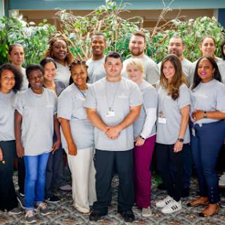 A diverse team gathered for a group photo in a lush outdoor setting.