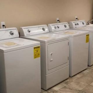 A row of washers and a dryer in a laundry room.