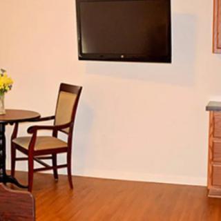 A cozy dining area with a small table and chairs, featuring a wall-mounted television and wooden flooring.