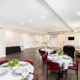 A modern dining room setup with tables and chairs, decorated with flowers, ideal for events.