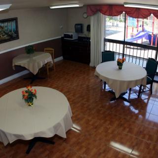 A dining area with round tables covered in white tablecloths, each adorned with a vase of flowers, near a large window.