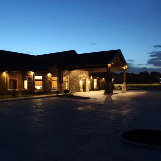 A building illuminated at dusk with exterior lights along the driveway.