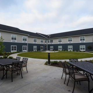A modern building with a spacious courtyard featuring outdoor seating and a well-maintained lawn.