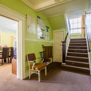 A traditional hallway with green walls featuring a staircase and adjoining dining room.