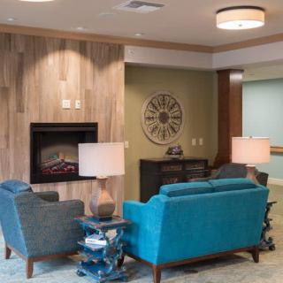 A modern living room featuring blue couches, a fireplace, and stylish decor.