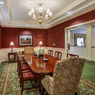 A traditional dining room with a wooden table, red walls, and an elegant chandelier.