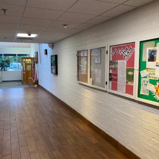 A well-lit school hallway featuring display cases with educational posters.