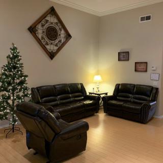 Cozy living room with a dark leather sofa set and decorated Christmas tree.