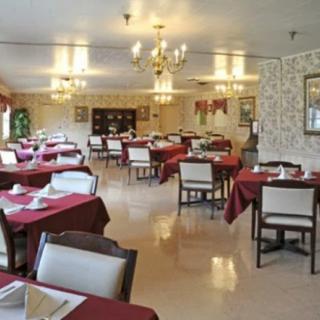 An elegant restaurant dining area with neatly arranged tables and chairs, featuring chandeliers.