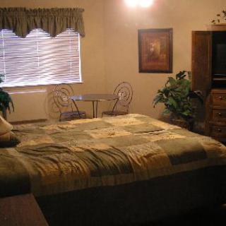 Cozy bedroom with a large bed, small table and chairs near the window.