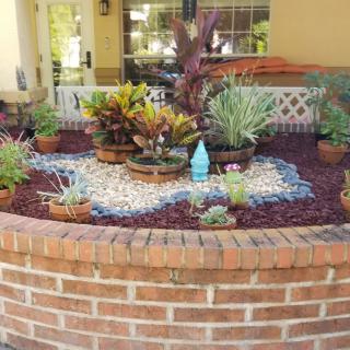 A beautifully arranged garden with a variety of succulents and decorative stones in a brick planter.
