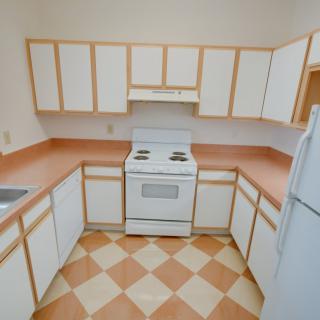 A small kitchen with white cabinets, a stove, and a refrigerator.