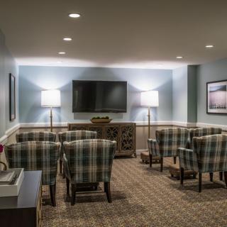 A cozy home theater setup with plaid chairs and a large television.