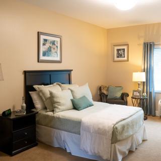 A cozy bedroom with a neatly made bed, decorative pillows, and elegant furniture.