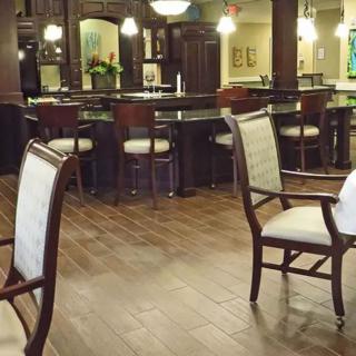 A cozy restaurant interior featuring a bar area with wooden chairs and warm lighting.