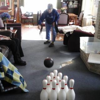 An elderly person enjoying a game of indoor bowling on a carpeted floor.