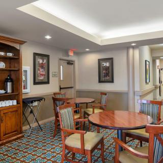 A cozy indoor dining area with wooden tables and chairs, decorative artwork, and warm lighting.