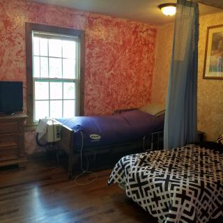 A cozy bedroom with two beds separated by a curtain, featuring a window and television.