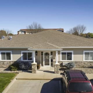 A suburban house with a driveway and parked cars on a sunny day.