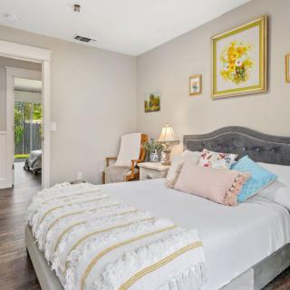 A cozy bedroom with stylish decor, featuring a bed with colorful pillows and wall paintings.