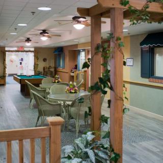 A cozy recreation room featuring a pool table, seating area, and wooden accents with plants.