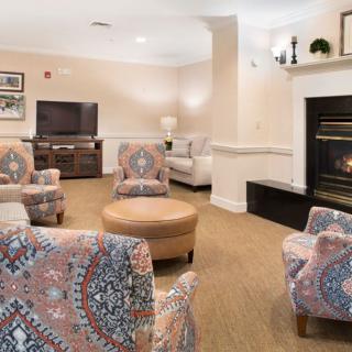 A cozy living room with patterned armchairs, a fireplace, and a television.