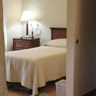 A cozy bedroom with a neatly made bed and a lamp on the nightstand.