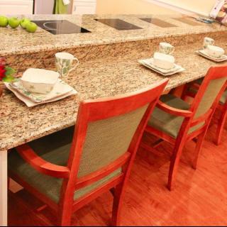 A stylish kitchen counter with granite top and bar stools set for dining.