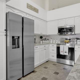 Modern kitchen with stainless steel appliances and white cabinetry.