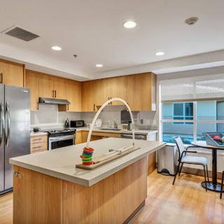 A stylish modern kitchen featuring wooden cabinets and a spacious island, perfect for cooking and dining.