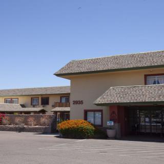 Exterior view of a hotel building with a parking area in front.
