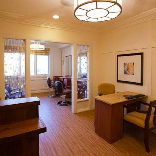 A well-lit office space featuring a desk, chairs, and large windows.