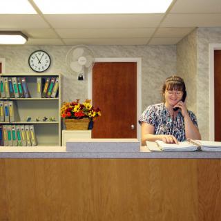 A woman sitting at a reception desk in an office setting.