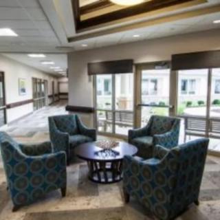 A cozy seating area in a modern lobby with four chairs around a small table, surrounded by large windows.