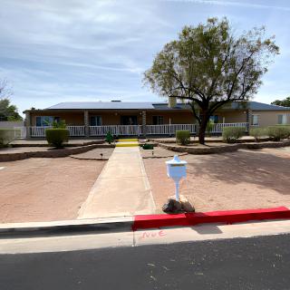 A suburban house with a long driveway, landscaped yard, and surrounding fence.