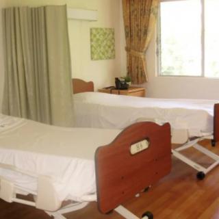 A hospital room with two beds and a large window allowing natural light.