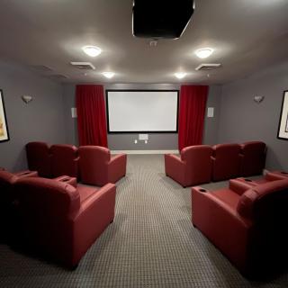 A cozy home theater with red armchairs and a large projector screen.