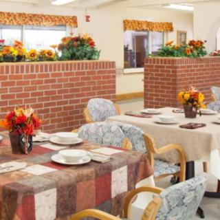 A cozy dining area with tables set for meals, featuring brick partitions and floral decorations.