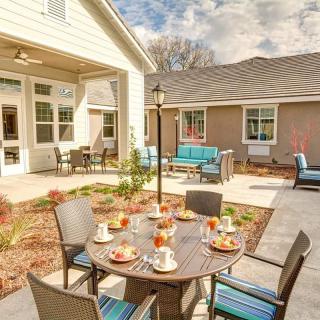A modern outdoor patio with a dining table set for guests on a sunny day.
