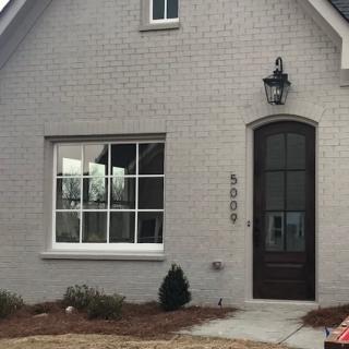 A charming house with a brick exterior and a lantern light by the front door.