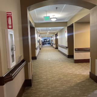 A spacious and well-lit hallway within a building, featuring carpet flooring and architectural details.