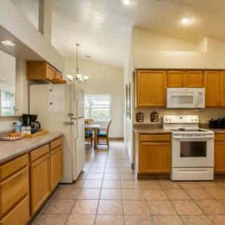 A modern kitchen with wooden cabinets, tiled flooring, and a dining area in the background.