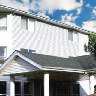 A residential building with a sloped roof and multiple windows set against a partly cloudy sky.