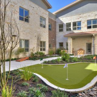 A courtyard with a mini golf course surrounded by modern architecture and greenery.