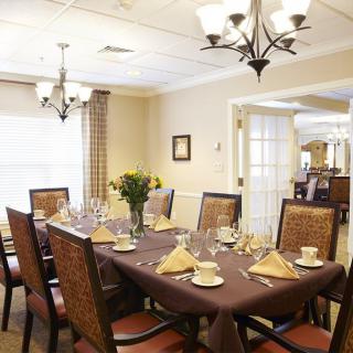 An elegantly set dining room with a large table, cushioned chairs, and ambient lighting.