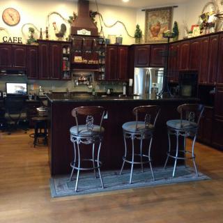 A kitchen with a central island and bar stools, featuring decorative elements and wooden flooring.