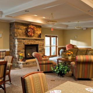 A cozy living room with a stone fireplace, comfortable armchairs, and warm decor.