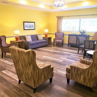 A cozy living room with yellow walls, featuring comfortable chairs and a sofa.