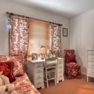 A cozy bedroom with a white desk and floral-patterned furnishings.