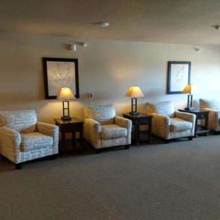 A spacious living area featuring a row of comfortable armchairs and side tables with lamps, adorned with framed artwork on the walls.